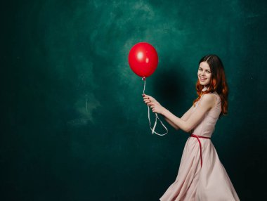 Kırmızı balonlu kadın yeşil arka planda tatil eğlencesi