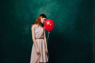 Kırmızı balonlu kadın yeşil arka planda tatil eğlencesi
