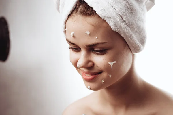 Веселая женщина с белым полотенцем на голове крем для лица уход за кожей — стоковое фото