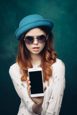 Mavi şapkalı şık bir kadın. Elinde telefon, iletişim teknolojisi var.