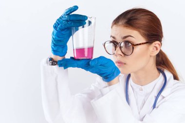 Bayan doktor mavi eldiven ve ilaç testleriyle masada oturuyor.