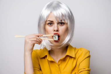 Beyaz peruklu güzel bir kadın ve Japon yemek çubuklarıyla suşi.