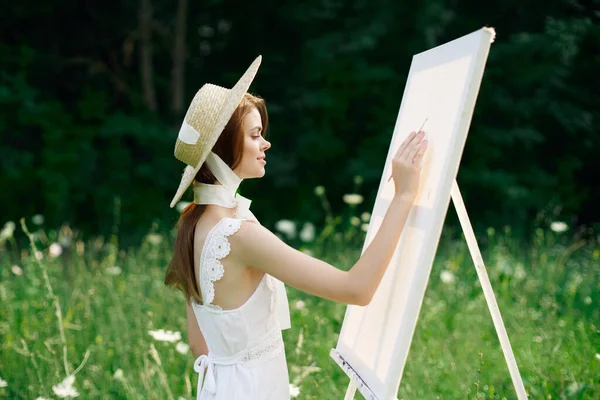 Γυναίκα σε λευκό φόρεμα στη φύση ζωγραφίζει μια εικόνα ενός χόμπι τοπίο — Φωτογραφία Αρχείου