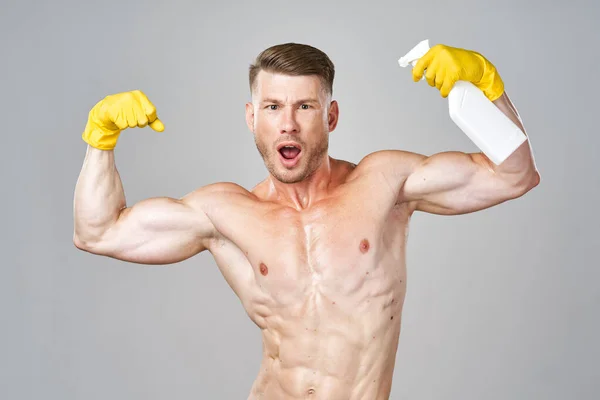 Pumped up man posing with detergent in rubber gloves — Stock Photo, Image