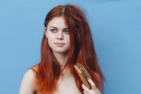 Красивая женщина расчесывает непослушные волосы синий фон — стоковое фото