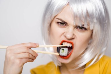 Beyaz peruklu güzel bir kadın ve Japon yemek çubuklarıyla suşi.