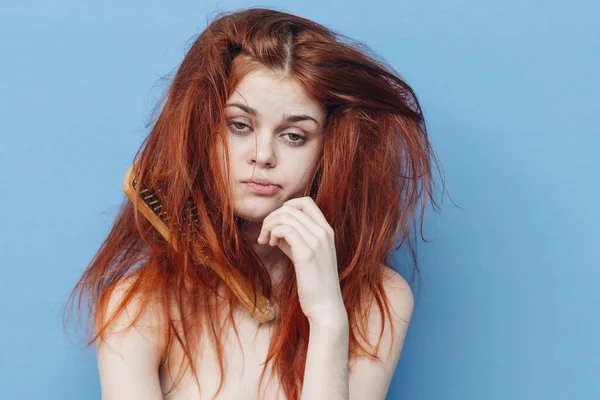 Kvinna med rött hår kam vård blå bakgrund — Stockfoto