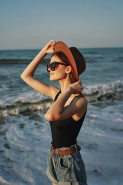 Kumsalda yürüyen bir kadın, tatil güneşinde seyahat ediyor.