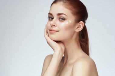 Çıplak omuzlu kadın yüz kremi cilt bakımına yakın çekim