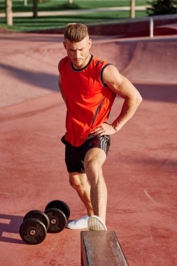 Sporcu adam dışarıda oyun sahasında spor yapıyor.