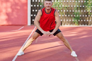 Spor sahasındaki spor salonunda kırmızı formalı bir sporcu.