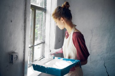 Önlüklü kadın, evin içini boyuyor.
