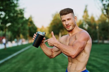 Parktaki egzersiz motivasyonunda kaslı vücutlu atletik bir adam.