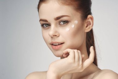 Bir kavanoz krem makyajlı kadın cilt bakımını yakından yapar.