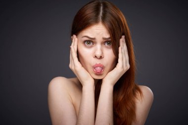 Güzel, kızıl saçlı, çıplak omuzlu, siyah arka plan pozu veren bir kadın.