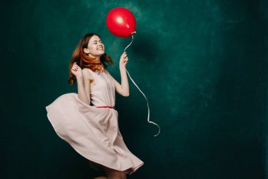 Kırmızı balonlu neşeli kadın yeşil arka plan tatili