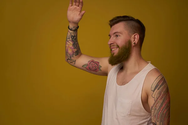 Macho man in white t-shirt tattoos on his arms posing isolated background — Stock Photo, Image