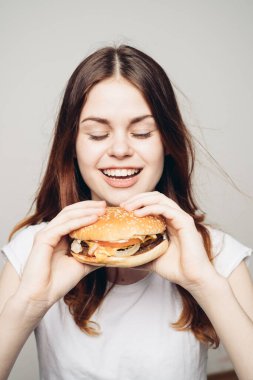 Elinde hamburger olan bir kadın. Atıştırmalık bir fast food.