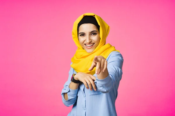 Femme gaie en jaune hijab technologie montre électronique utilisateur fond rose — Photo