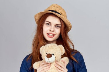 Oyuncak ayıyla şapkalı neşeli kadın.