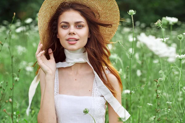 Vacker kvinna i vit klänning och hatt poserar blommor natur — Stockfoto