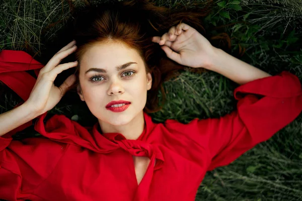 Mulher em vestido vermelho encontra-se na grama endereço moda verão — Fotografia de Stock