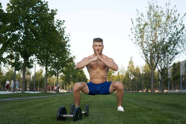 Homme musclé dans le parc s'entraînant avec des haltères — Photo