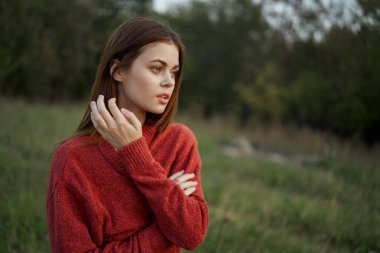 Kırmızılı bir kadın, dışarıda bir tarlada yürüyor.