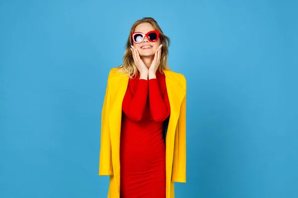 Mujer en chaqueta amarilla posando maquillaje moda fondo azul — Foto de Stock