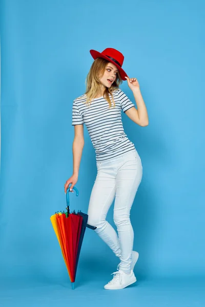 Mooie vrouw mode poseren kleurrijke paraplu blauwe achtergrond — Stockfoto