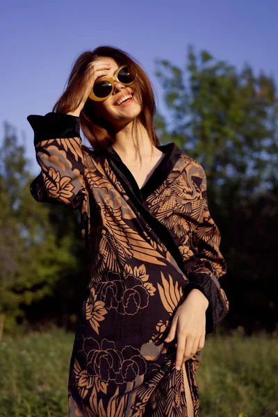 Şık giyinmiş güzel bir kadın güneş gözlüğü takıyor.