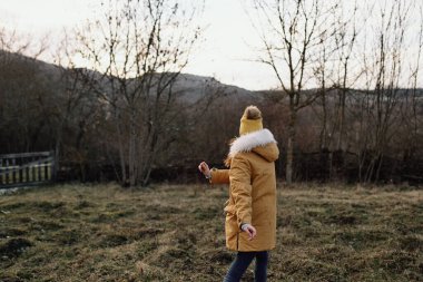 Dışarıda ceketli bir kadın sonbaharda temiz hava alıyor.