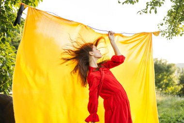 Kırmızı elbiseli neşeli bir kadın elleriyle işaret ediyor.