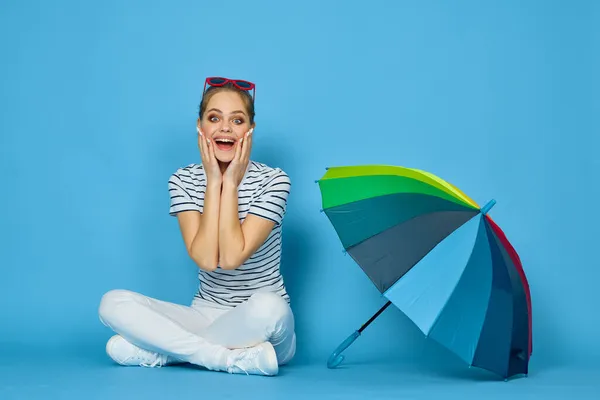 Vacker kvinna mode poserar färgglada paraply blå bakgrund — Stockfoto