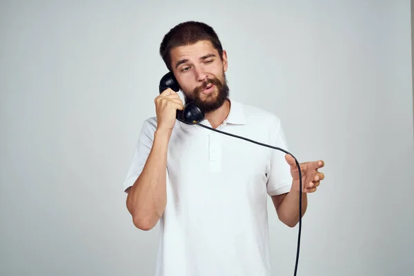 Emotional bearded man talking on retro phone light background — Stock Photo, Image