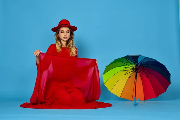 Kvinna i röd klänning flerfärgad paraply blå bakgrund — Stockfoto