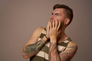 Kollarında çizgili formalı hippi dövmeleri olan ulusal sakallı bir adam.