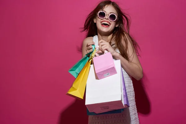 Vidám nő csomagokkal a kezében Shopaholic rózsaszín háttér — Stock Fotó