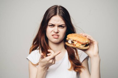 Elinde hamburger olan bir kadın. Atıştırmalık bir fast food.