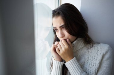 Beyaz kazaklı esmer, depresyondan dışarı bakıyor.