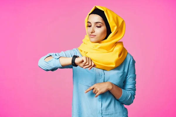 Femme portant hijab jaune technologie montre électronique fond rose — Photo