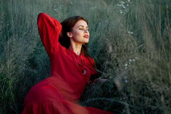 Mulher bonita em vestido vermelho encontra-se na grama natureza sol — Fotografia de Stock