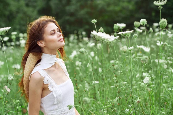 Vacker kvinna i vit klänning i ett fält blommor natur — Stockfoto