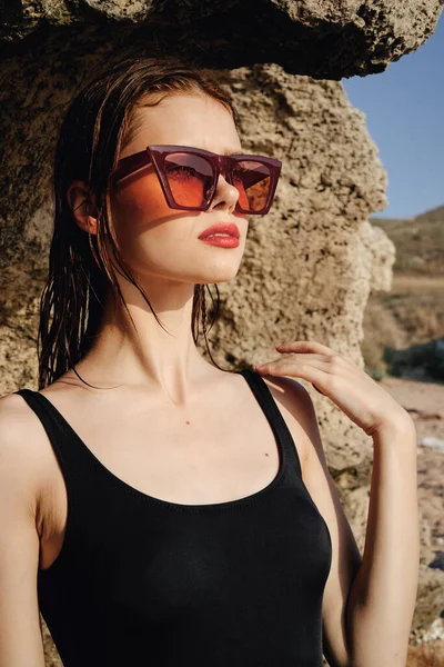 Woman wearing sunglasses swimsuit dispensing rocks travel — Stock Photo, Image