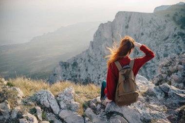 Kadın yürüyüşçü dağ manzarasında oturuyor. Temiz hava.