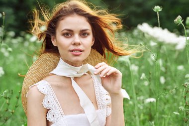 Beyaz elbiseli, tarla çiçekleri içinde güzel bir kadın.