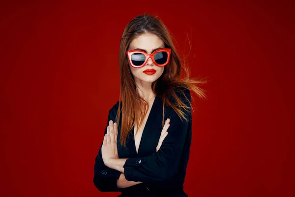 Bonita mujer usando gafas de sol moda posando peinado rojo fondo — Foto de Stock
