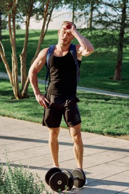 Parkın spor salonunda dambılı bir adam.