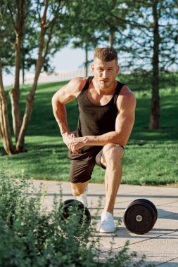 Dambılı atletik adam dışarıda motivasyon egzersizi yapıyor.