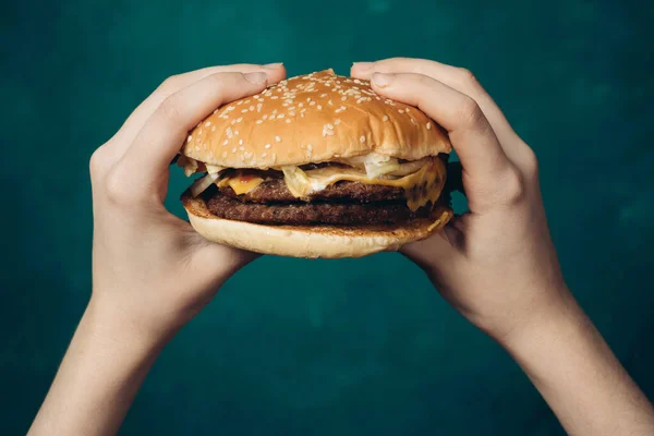Hamburger in mani primo piano fast food sfondo verde — Foto Stock